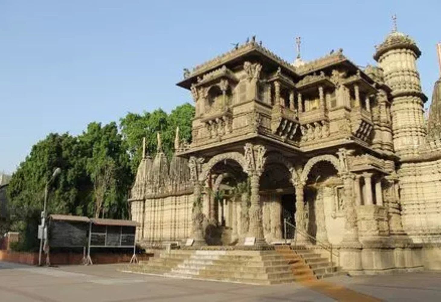 A vibrant street view of Ahmedabad’s old city showing a blend of temples, mosques and historic havelis, with narrow lanes, carved facades and people walking through the heritage neighbourhood A vibrant street view of Ahmedabad’s old city showing a blend of temples, mosques and historic havelis, with narrow lanes, carved facades and people walking through the heritage neighbourhood